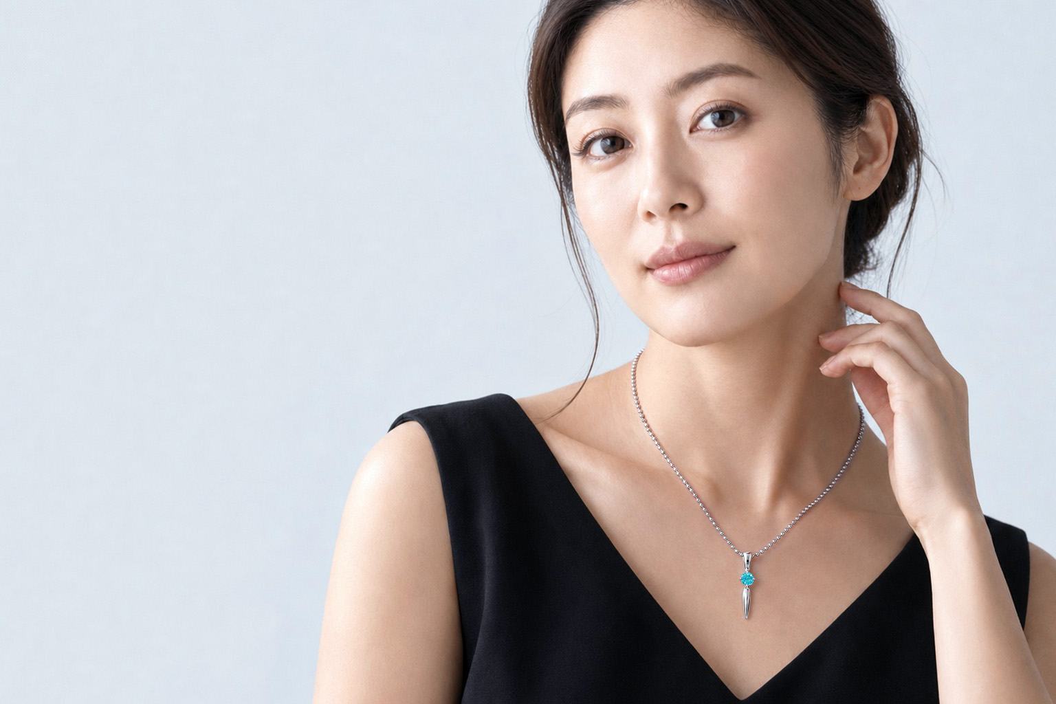 ブルーの宝石が付いたネックレスを着用した同じ女性